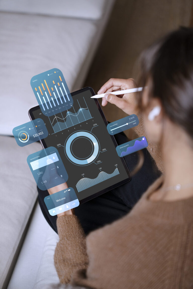 Uma pessoa usando uma caneta stylus em um tablet exibindo vários gráficos digitais, tabelas e visualizações de dados - ferramentas gestão casa - enquanto está sentada em um sofá.