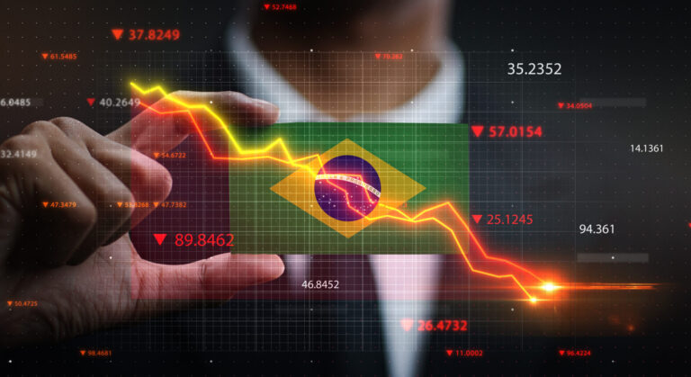 Uma pessoa segura um cartão transparente com a bandeira do Brasil, sobreposta a um gráfico do mercado de ações com tendência de queda e dados financeiros, simbolizando como a crise econômica no Brasil afeta os negócios do país.